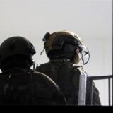 Spezialkräfte der Polizei stehen im Hausflur eines Mehrfamilienhauses.