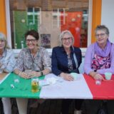 Frauen sitzen an einem Tisch, der mit einer italienischen Fahne geschmückt ist.