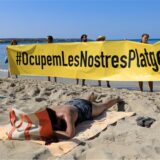 Leute halten an einem Strand auf Mallorca ein Banner „#Besetzen wir unsere Strände“ aus Protest gegen den Massentourismus auf der Balearen-Insel.