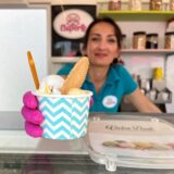 Eine Mitarbeiterin der Eisperle in Dortmund hält einen Eis-Becher ins Bild.