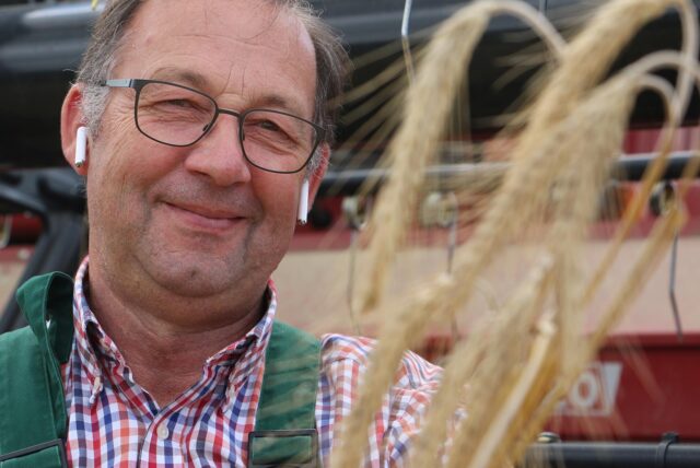 Hans-Heinrich Wortmann bei der Ernte. Er zeigt Triticale-Ähren, eine ertragreiche und widerstandfähige Kreuzung aus Roggen und Weizen.