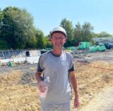 Bauarbeiter Mario Fricke steht auf einer Baustelle mit einer Flasche Wasser in der Hand