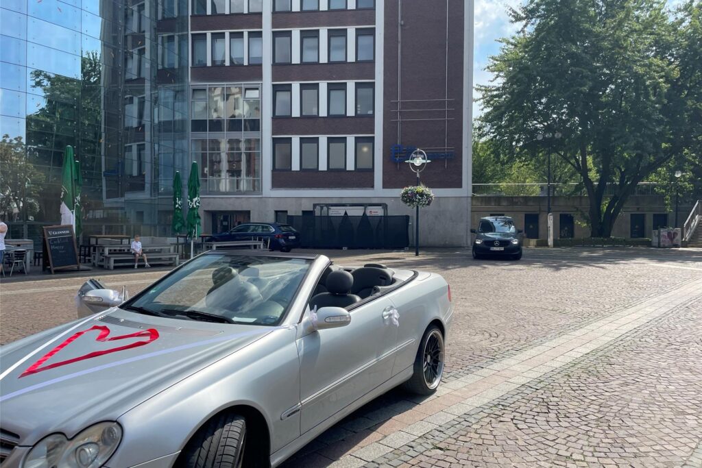 Ein silbernes Cabrio steht auf dem Friedensplatz. Ein Herz ist mit einem roten Band auf der Motorhaube ausgelegt. Ein silbernes Cabrio steht auf dem Friedensplatz. Ein Herz ist mit einem roten Band auf der Motorhaube ausgelegt.