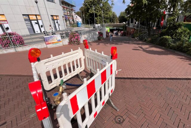 Am Ende der Unnaer Fußgängerzone, zwischen dem Einkaufscenter Neue Mühle und dem Rathaus, müssen Passanten um Gelsenwasser-Absperrungen manövrieren.