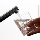 Eine Person hält ein Glas Wasser unter einen Wasserhahn und lässt es voll laufen (Symbolbild).