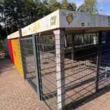 Am Bahnhof Königsborn in Unna steht ein Käfig aus Stabmattenzaunelementen. Pfosten und Dach im Inneren weisen viele Aufkleber und Graffiti auf.