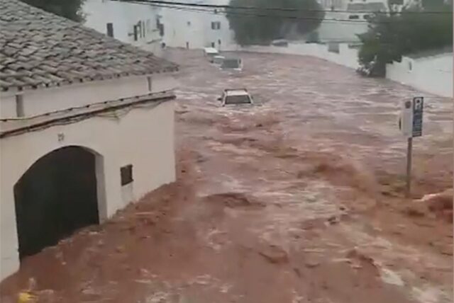 Braune Wassermassen fließen zwischen den Häusern bei schwerem Unwetter.