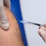 Eine Mitarbeiterin impft einen Wirkstoff in einen Arm.