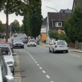 Zu sehen ist ein Auto auf einer Straße. Rechts und links stehen Häuser.