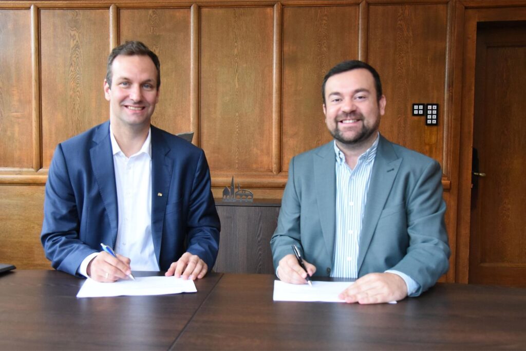 Sebastian Kirchmann (Stadtwerke Schwerte) und Dimitrios Axourgos (Bürgermeister Schwerte) sitzen an einem Tisch und unterschreiben zwei Zettel. Sebastian Kirchmann (Stadtwerke Schwerte) und Dimitrios Axourgos (Bürgermeister Schwerte) sitzen an einem Tisch und unterschreiben zwei Zettel.
