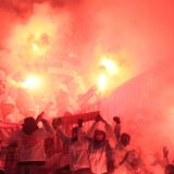 Vermummte Menschen halten Fanschals hoch und zünden Pyrotechnik.
