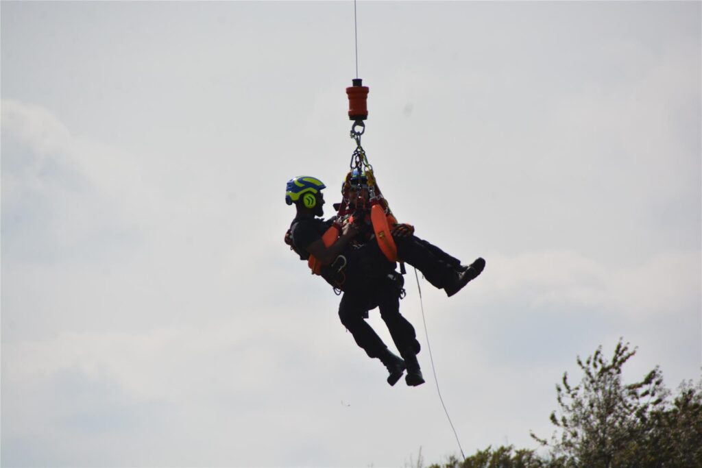 Zwei Personen hängen an der Winde eines Hubschraubers. Zwei Personen hängen an der Winde eines Hubschraubers.