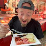 Ein Mann zeigt einen Teller mit Fleisch und Käse auf dem Streetfood-Markt in Schwerte.