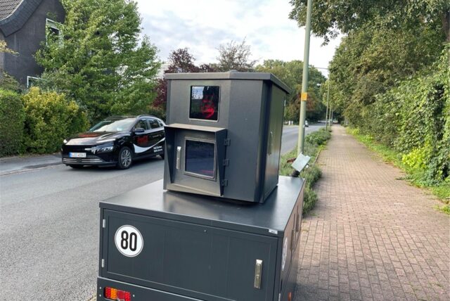 Ein Blitzer steht auf dem Gehweg in Richtung Straße.