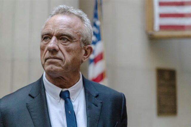 Portrait von Robert F. Kennedy Jr. mit der amerikanischen Flagge im Hintergrund.
