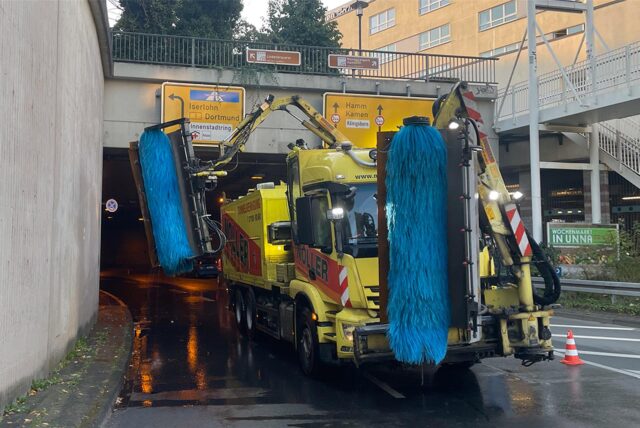 Eine Reinigungsmaschine steht entgegen der Fahrtrichtung am Ausgang des Ringtunnels in Unna. Zwei Arbeiter sperren derweil die Fahrbahn ab
