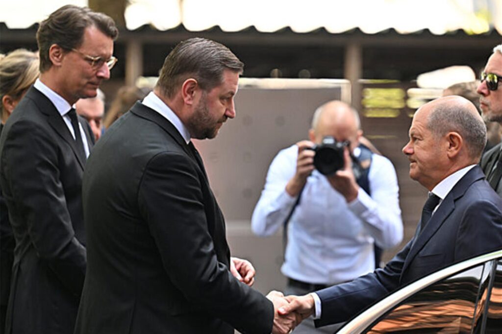 Bundeskanzler Olaf Scholz (SPD, r) wird von NRW-Ministerpräsident Hendrik Wüst (CDU; l) und von Tim Kurzbach (SPD, M), Oberbürgermeister der Stadt Solingen, begrüßt.