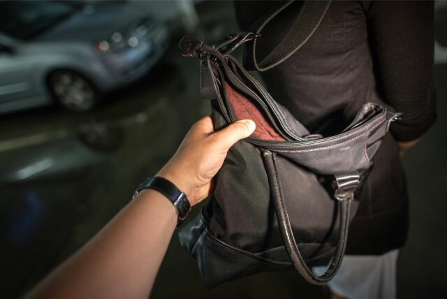 Eine Person greift nach einer Handtasche (Symbolbild)