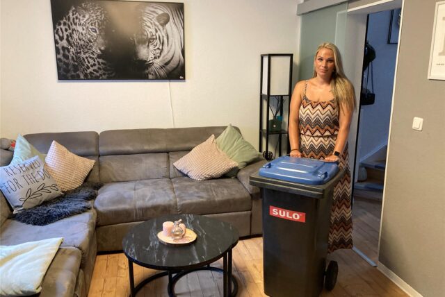 Nicole Siegling steht mit ihrer Papiertonne im Wohnzimmer ihres Reihenhauses in Marl-Brassert.