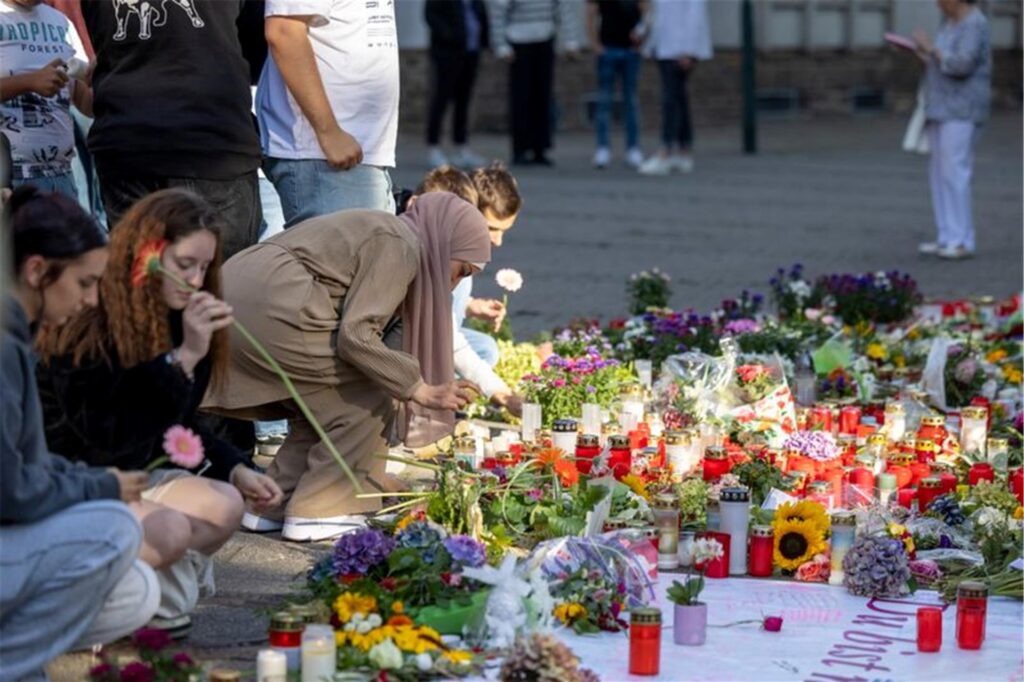 Menschen legen in der Nähe des Tatorts in Solingen Blumen und Kerzen zum Gedenken der Opfer nieder.