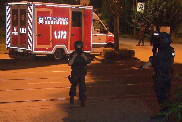 SEK-Beamte stehen während eines Einsatzes in Dortmund-Dorstfeld vor einem Rettungswagen.