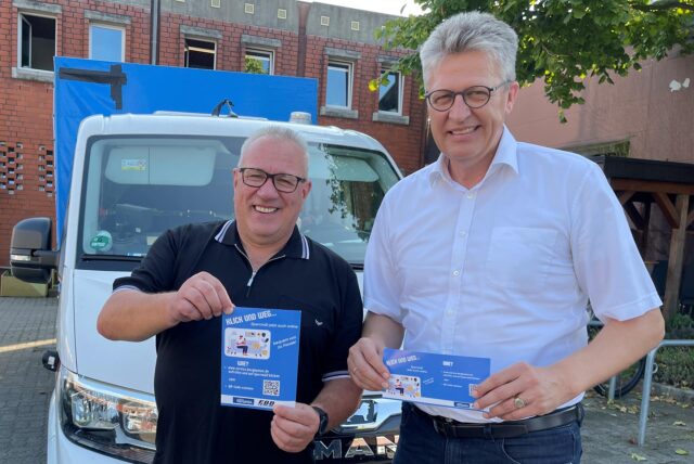 Bernd Schäfer (rechts) und Stefan Polplatz, vom EBB Bergkamen, halten den Flyer von „Sperrmüll-Online“ in die Kamera.