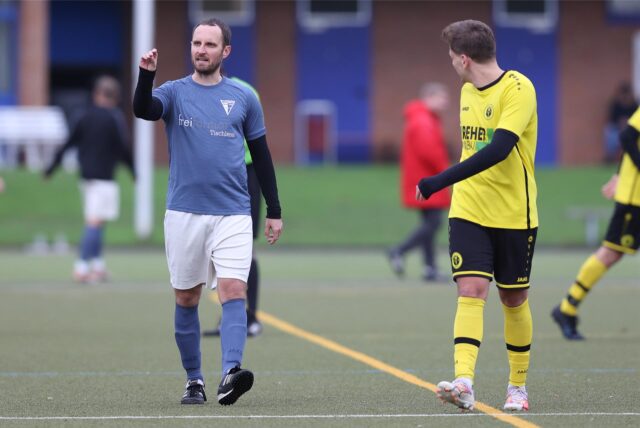 Janis Leenders (l.) im Dress vom Werner SC II gibt auf dem Platz Anweisungen. Ein Spieler vom SC Capelle läuft vorbei.
