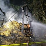 Brennende Strohballen werden mithilfe eines Wasserstrahls von der Feuerwehr gelöscht.