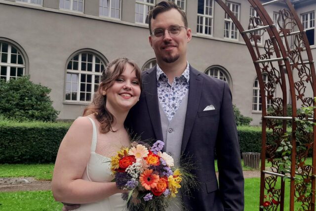 Alexandra und Sven stehen frisch verheiratet vor dem Schwerter Rathaus.