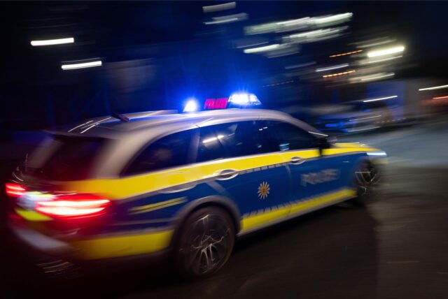 Ein Polizeiauto fährt schnell mit Blaulicht über eine Straße.