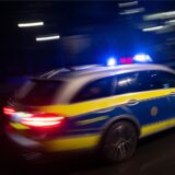 Ein Polizeiauto fährt schnell mit Blaulicht über eine Straße.