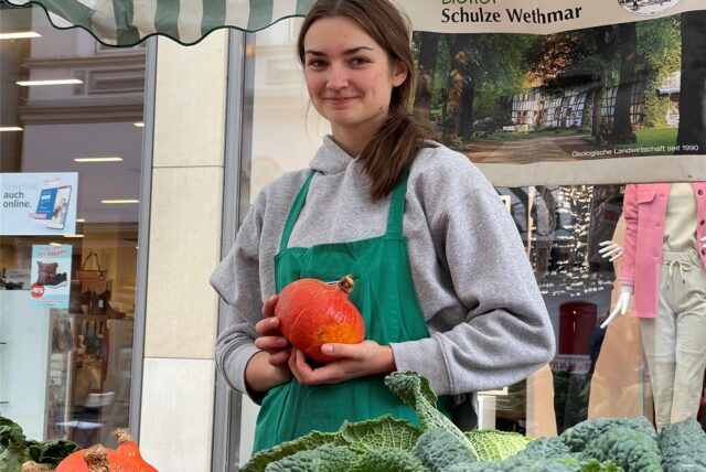 Eine Frau hält einen Kürbis in die Hand.