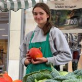 Eine Frau hält einen Kürbis in die Hand.