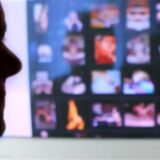 Eine Person schaut auf einen Monitor mit verschwommenen pronografischen Bildern.