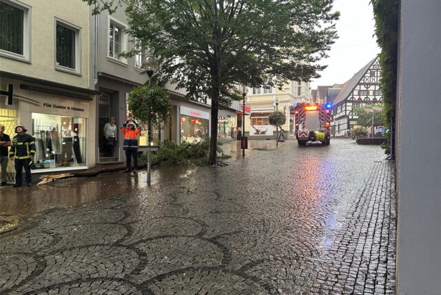 Ein Feuerwehrauto fährt durch die Fußgängerzone in Unna. Äste liegen auf dem Boden.