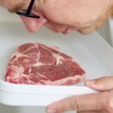 Ein Lebensmittelkontrolleur riecht an einem Stück Fleisch.