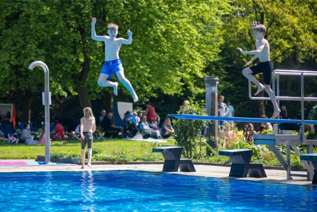 Jungen springen im Freibad Dellwig vom Sprungturm ins Becken