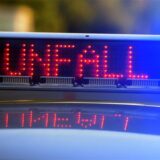 Auf einem Polizeifahrzeug warnt eine Leuchtschrift vor einer Unfallstelle.