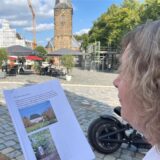 Karin Störmer sitzt am Marktplatz in Schwerte und hält einen Brief hoch.