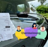 Ein Strafzettel am Scheibenwischer eines falsch parkenden Wohnwagens.