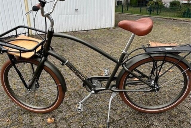 Ein schwarzes Pedelecc mit braunen Reifen und einem braunen Sitz steht vor Garagen