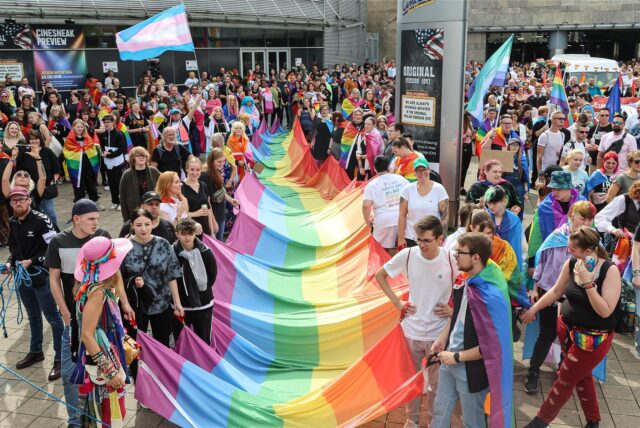 Teilnehmende des Christopher Street Day in Dortmund halten im Jahr 2023 eine große Pride-Flagge.