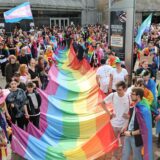 Teilnehmende des Christopher Street Day in Dortmund halten im Jahr 2023 eine große Pride-Flagge.