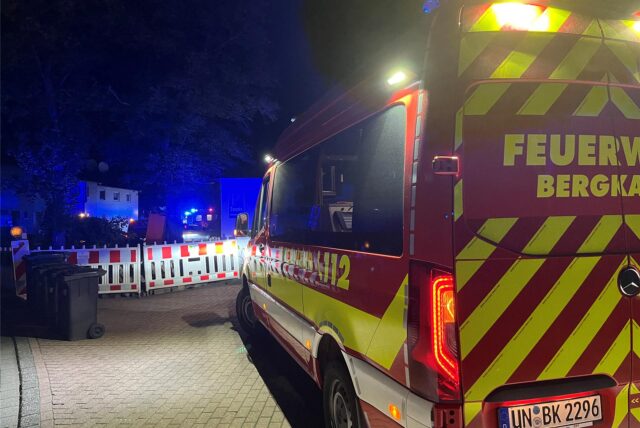 Ein Einsatzfahrzeug der Bergkamener Feuerwehr steht in der Nacht an einer Straßenabsperrung.