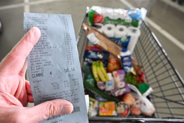 Ein Verbraucher hält nach einem Einkauf in einem Supermarkt einen Kassenzettel in der Hand.