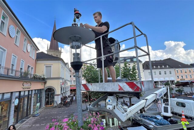 Ein Techniker auf einer Hebebühne installiert eine Überwachungskamera in der Unnaer Innenstadt