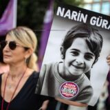 Eine Demonstrantin hält ein Porträt von Narin Guran hoch.