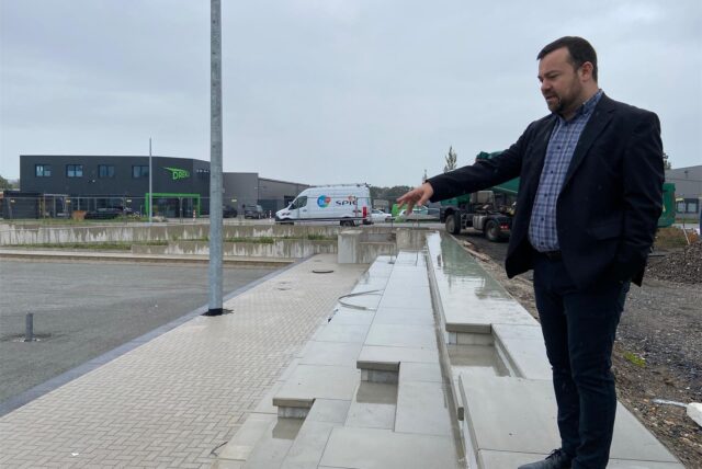 Bürgermeister Dimitrios Axourgos steht auf dem Gelände der neuen Sportarena in Schwerte-Wandhofen, er zeigt auf das Beach-Volleyballfeld.