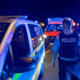 Ein Polizist steht nachts während eines Einsatzes auf dem Stadtfest in Unna neben einem Streifenwagen. Im Hintergrund ist ein Rettungswagen.