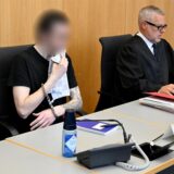 Der Angeklagte sitzt im Landgericht in Ulm. Er hält sich ein Spültuch vor dem Mund, weil er durch die Schüsse eines Polizisten am Kiefer verletzt wurde und nun nicht mehr richtig trinken kann.
